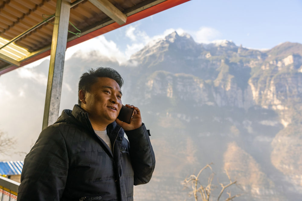 On February 14, 2023, in Gulu Village, Yongli Yi Ethnic Township, Hanyuan County, Sichuan Province, Zheng Wangchun communicated with foreign tourists by phone about visiting and accommodating in the village. Photo by Xinhua News Agency reporter Shen Bohan